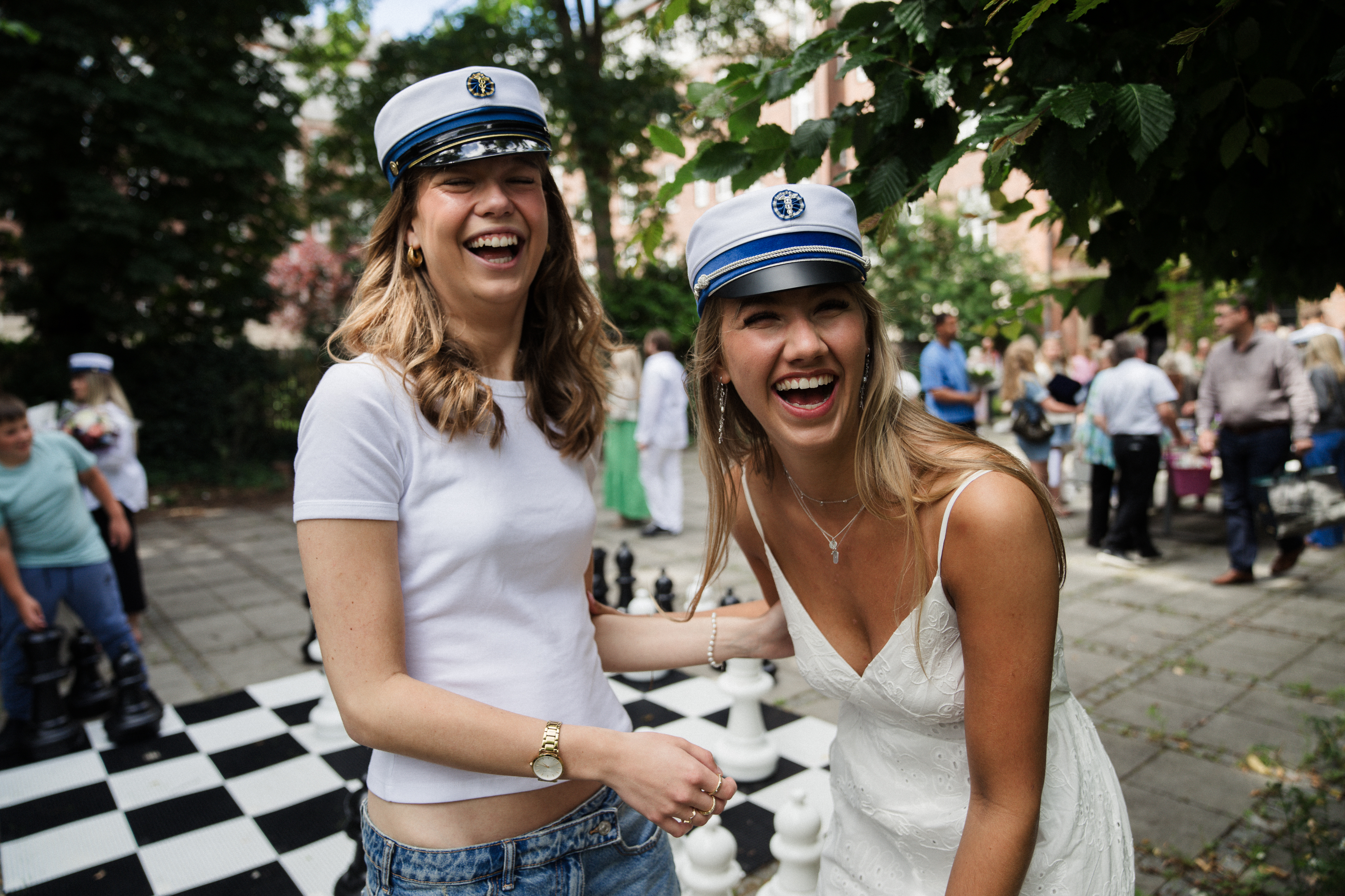 To elever med studenterhue på står og griner