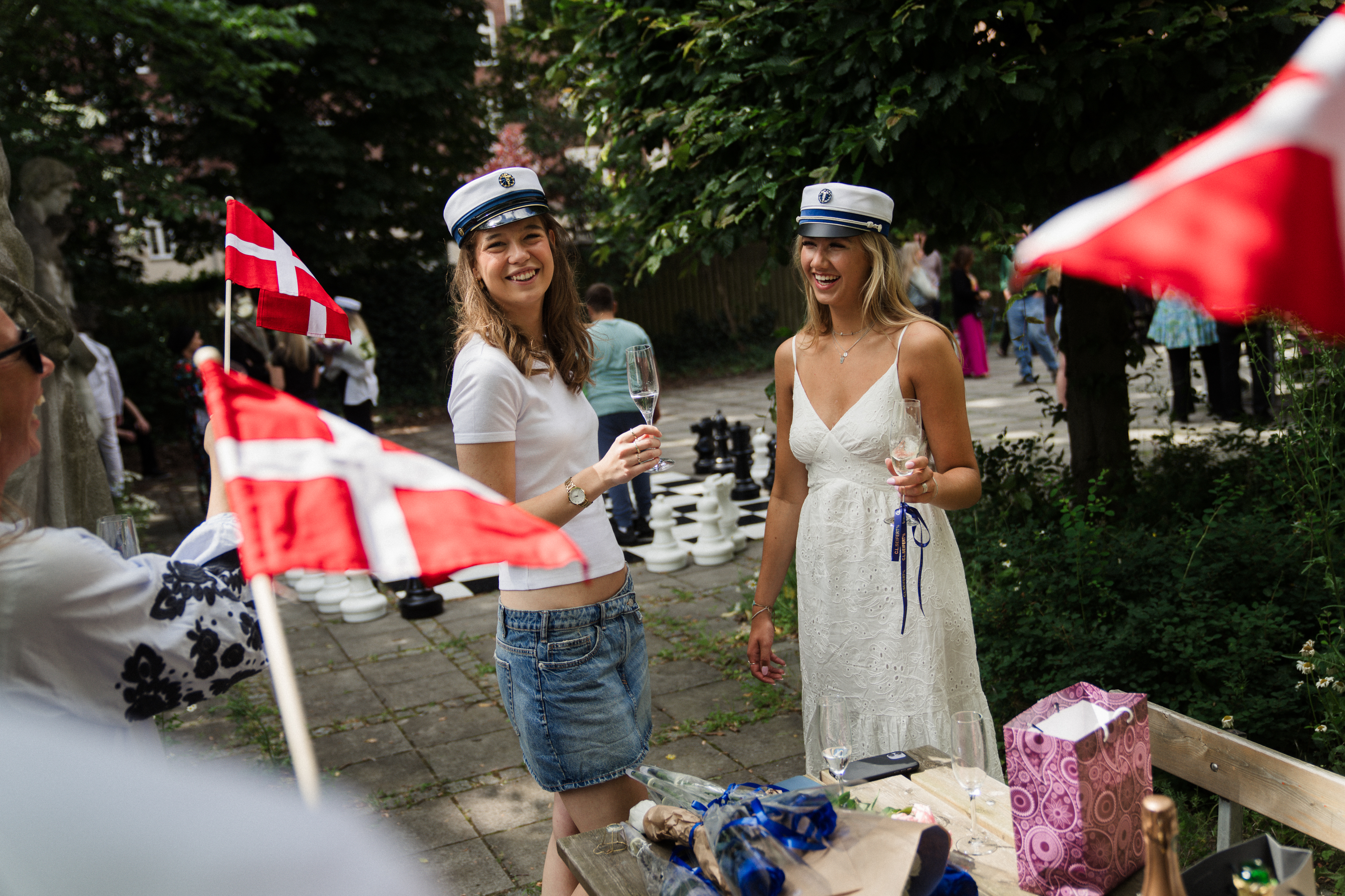 To elever står med studenterhue på og får et glas champagne
